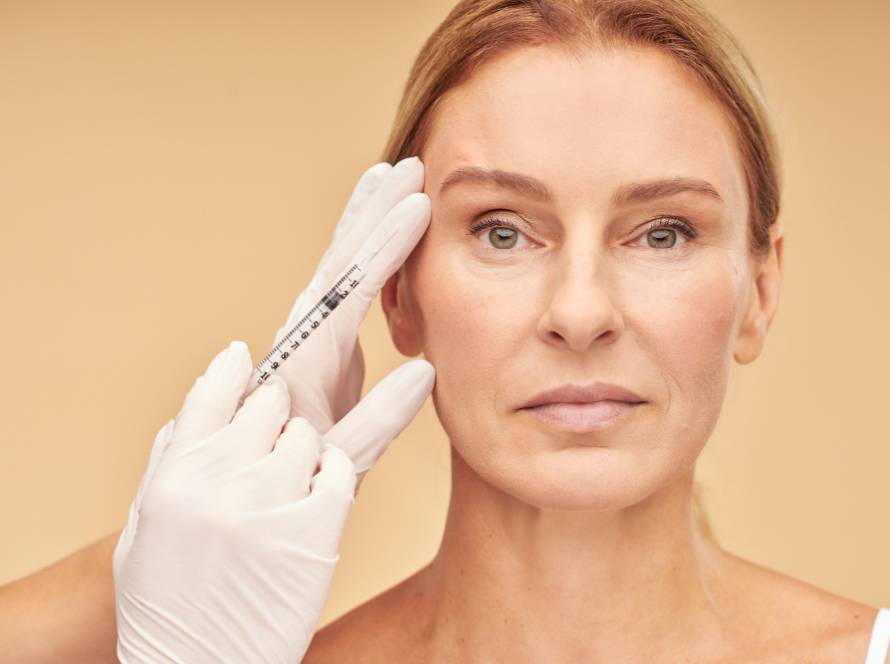 Mature woman receiving dermal filler injection near eyes – catalog image, not a real patient